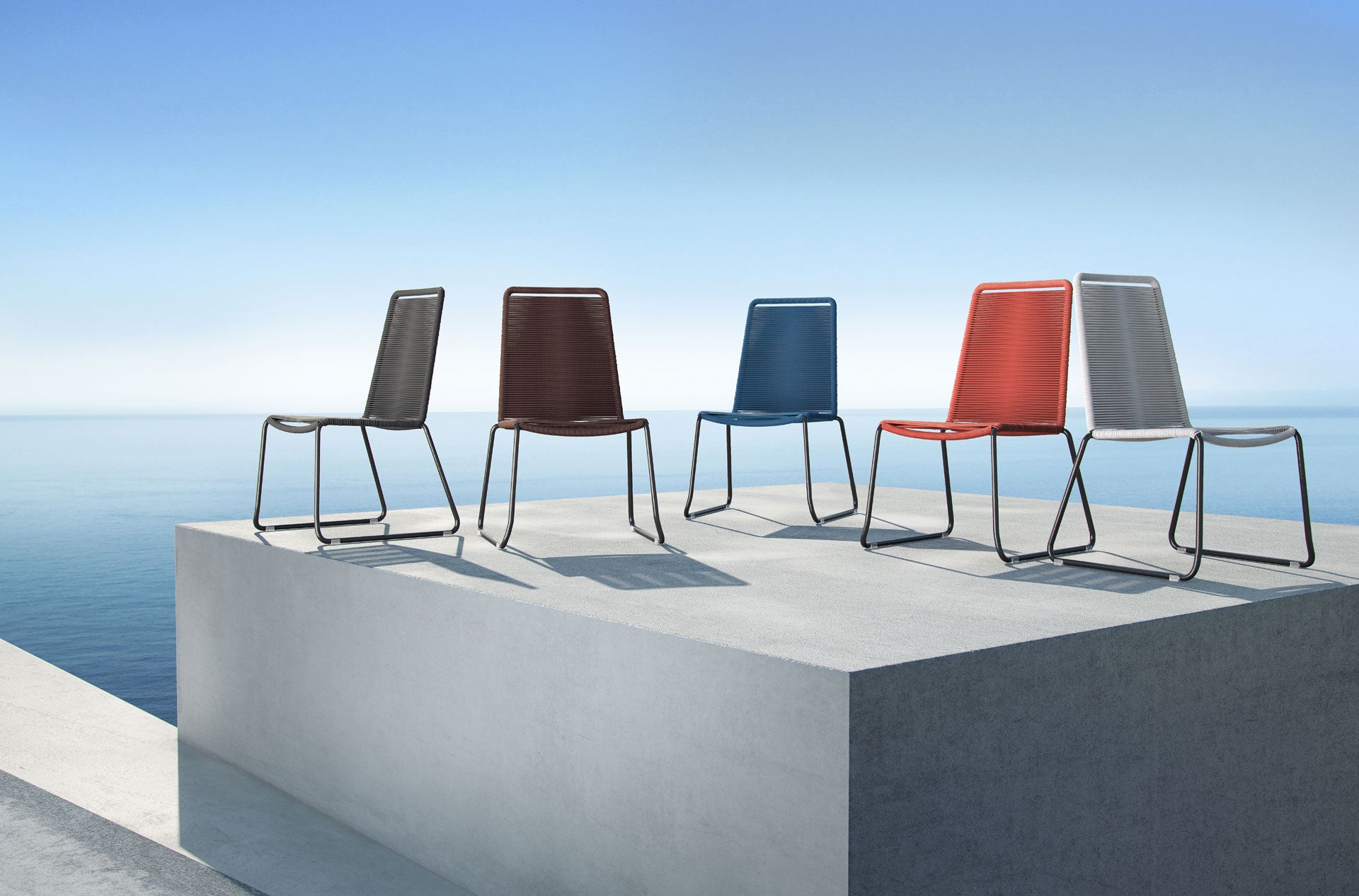 5 different colored chairs made from green materials sitting on a stone surface.